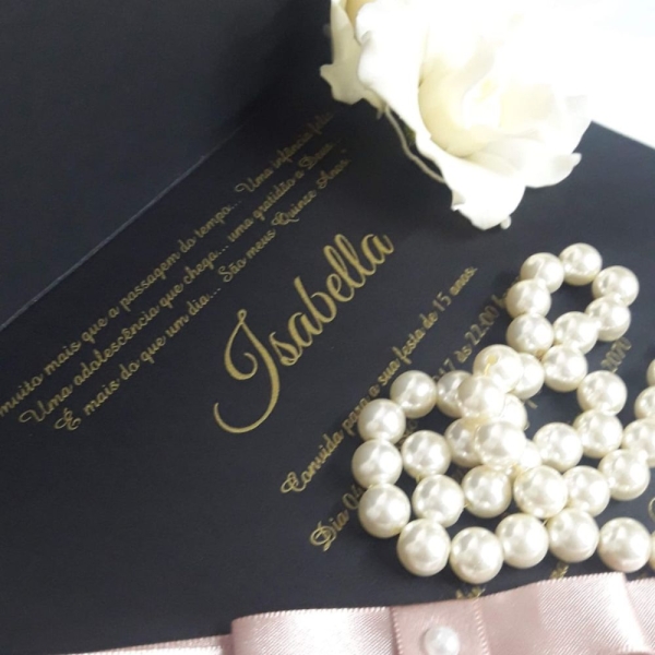 Que Encanta à Primeira Vista A celebração dos 15 anos é um dos momentos mais marcantes na vida de uma jovem. Conhecida como a festa de debutante, essa ocasião representa a transição da infância para a juventude e merece ser anunciada com todo o charme, sofisticação e personalidade. E tudo começa com o convite. Mais do que apenas um informativo sobre data e local, o convite de 15 anos é o primeiro contato dos convidados com o estilo e a essência da festa. Por isso, convidar com elegância é essencial. Neste post, vamos apresentar uma verdadeira obra de arte: um modelo de convite debutante que une delicadeza, exclusividade e sofisticação. Ele foi pensado para encantar desde o primeiro olhar e ficar guardado como lembrança desse dia tão especial. Se você está buscando inspiração para criar um convite inesquecível, continue lendo e descubra cada detalhe desta peça única. O Encanto Começa pelo Exterior O primeiro impacto do convite de 15 anos acontece no momento em que ele é entregue. Este modelo é confeccionado em um papel rosa brilhante de alta gramatura, que oferece uma textura luxuosa e um brilho sutil que reflete a luz com suavidade. O tom de rosa escolhido remete à feminilidade e à doçura dessa fase da vida, enquanto o brilho acrescenta um toque de glamour e celebração. Para selar o convite com ainda mais requinte, utilizamos um delicado lacre de cera em tom rosé, que carrega o símbolo de um brasão personalizado com as iniciais da debutante. O lacre é decorado com uma pequena flor sempre-viva, que adiciona um toque artesanal e romântico, remetendo à ideia de eternidade – afinal, os momentos especiais devem ser eternizados. A Magia Continua por Dentro Ao abrir o convite, o encantamento só aumenta. O conteúdo interno é impresso em papel Aspen, conhecido por sua leveza, textura acetinada e excelente qualidade de impressão. O design foi cuidadosamente desenvolvido para refletir a personalidade da debutante e o estilo da festa. O layout conta com uma composição de flores silvestres em aquarela, distribuídas de forma harmônica nas bordas, trazendo a sensação de um jardim delicado e natural. Essas flores não apenas embelezam o convite, mas também transmitem frescor, leveza e a alegria típica dos 15 anos. O centro do convite é reservado para o texto principal, onde as informações da festa são dispostas de forma clara e elegante. O grande destaque é o nome da debutante, que aparece em hot stamp rosé, uma técnica que aplica uma camada metálica brilhante em alto relevo, criando um efeito visual sofisticado e memorável. Este detalhe atrai o olhar imediatamente, valorizando ainda mais o nome da aniversariante e demonstrando a importância da ocasião. O brasão que aparece no lacre é repetido discretamente no topo do convite, integrando o design com consistência e refinamento. Ele simboliza a nobreza e a tradição da cerimônia de debutante, ao mesmo tempo que imprime um ar moderno e exclusivo. Convidando com Elegância e Personalidade Esse modelo de convite debutante foi criado para quem deseja convidar com elegância, expressando carinho e cuidado com cada convidado. A escolha dos materiais, as técnicas de impressão e os elementos decorativos foram pensados para transmitir sofisticação e personalidade, revelando um pouco do que os convidados podem esperar da celebração. Afinal, o convite de 15 anos não é apenas um pedaço de papel: ele é o cartão de visitas da festa, o primeiro capítulo de uma história inesquecível. Ele antecipa emoções, desperta expectativas e faz cada pessoa se sentir especial e desejada para compartilhar esse momento tão único. Se você está planejando uma festa de 15 anos e quer impressionar desde o primeiro detalhe, inspire-se neste modelo de convite e transforme o anúncio da sua celebração em uma verdadeira experiência. Aposte em materiais nobres, toques personalizados e, acima de tudo, convidando com elegância. Porque os 15 anos passam, mas a memória de um convite bem feito dura para sempre.